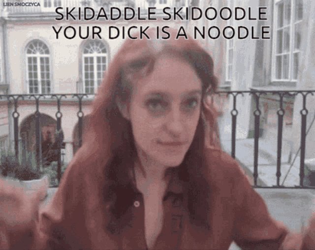 a woman with red hair is sitting on a balcony with the words skidaddle skidoodle your dick is a noodle above her