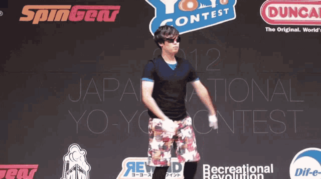 a man stands in front of a yoyo contest sign