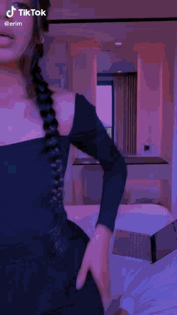 a woman with braids is standing in a room with tiktok written on the bottom of the screen