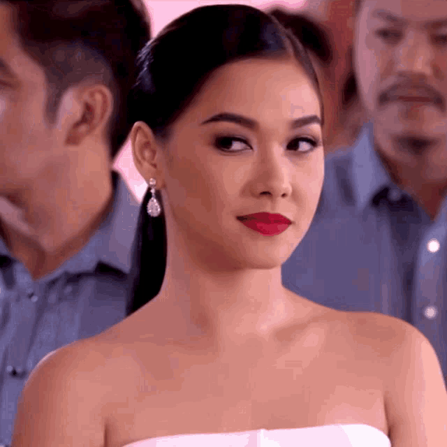 a woman in a white strapless dress with red lipstick and earrings