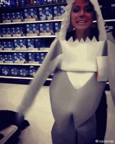 a woman in a shark costume is standing in front of shelves