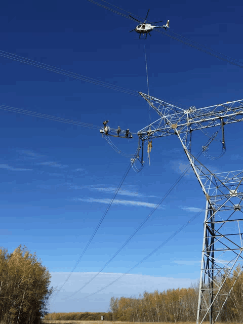 a helicopter is working on a power line in the middle of a field