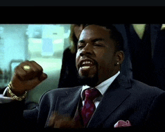 a man in a suit and tie holds his fist up