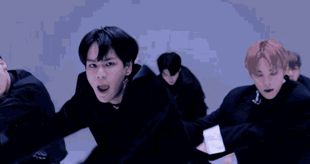a group of young men are dancing together in front of a blue background .