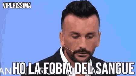 a man with a beard is wearing a suit and tie and has a microphone in his ear .