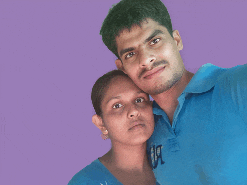a man and woman are posing for a picture and the man is wearing a blue shirt with the letter a on the front