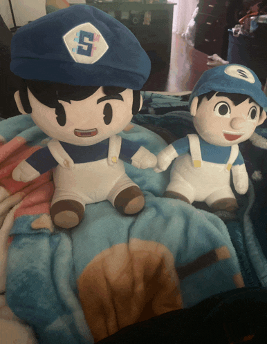 two stuffed toys one of which has the letter s on his hat