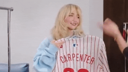 a woman is holding a baseball jersey hanging on a rack .
