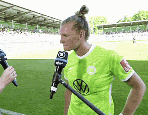 a woman in a green shirt is being interviewed by a microphone that says nbc