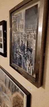 three framed paintings are hanging on a wall one of which is a reflection of a city