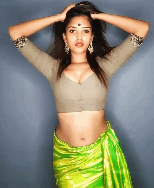 a woman wearing a crop top and a green striped saree