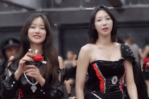 two women are standing next to each other and one is holding a flower