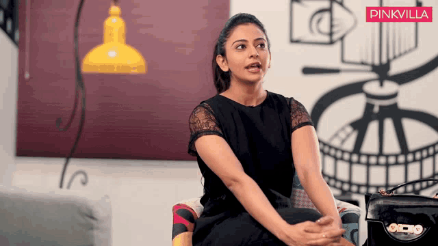 a woman is sitting in a chair with a pinkvilla logo in the corner