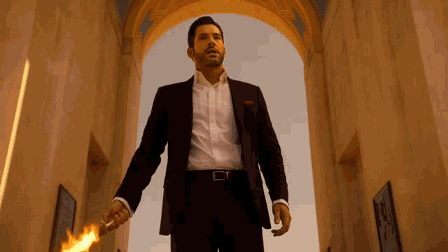 a man in a suit and white shirt holds a torch