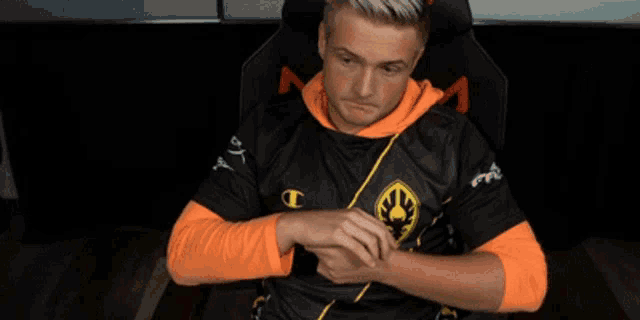 a man wearing a black and orange shirt with a champion logo on it