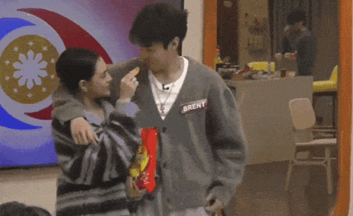 a man wearing a name tag that says ' trent ' on it kisses a woman