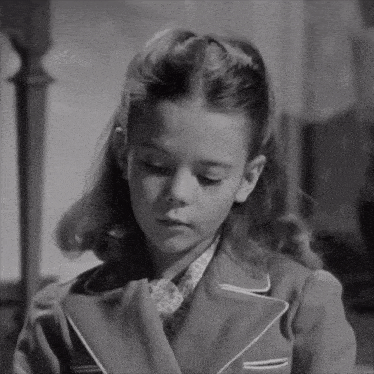 a black and white photo of a young girl wearing a coat