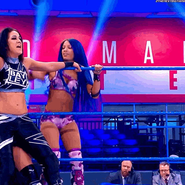 two female wrestlers are in a ring with a sign that says mai
