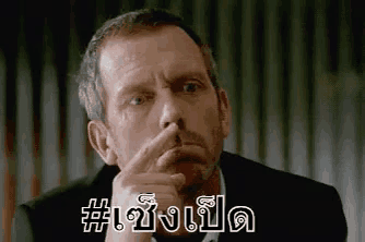 a man in a suit is making a funny face with his finger in his nose .