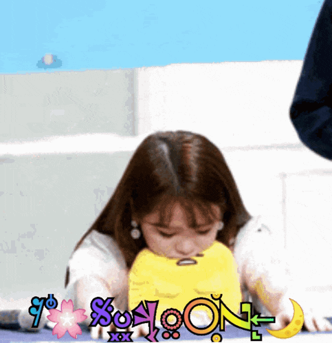 a girl is playing with a yellow toy that says noon on it