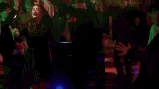 a man singing into a microphone in a dark room with purple lights behind him