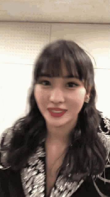 a close up of a woman 's face with red lipstick and a sequined jacket .