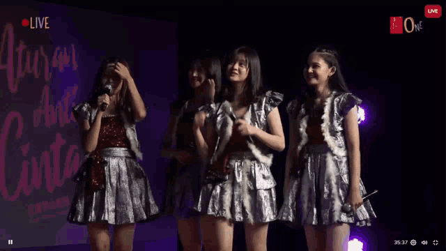 a group of girls are standing on a stage with microphones in their hands .