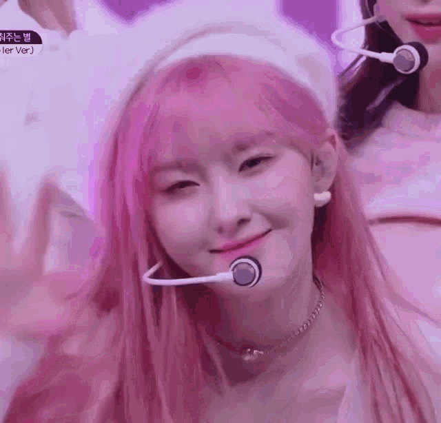 a girl with pink hair is wearing a headband and a microphone .