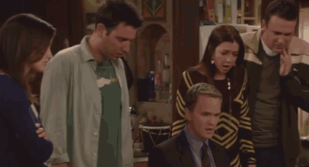 a group of people are standing around a man in a suit