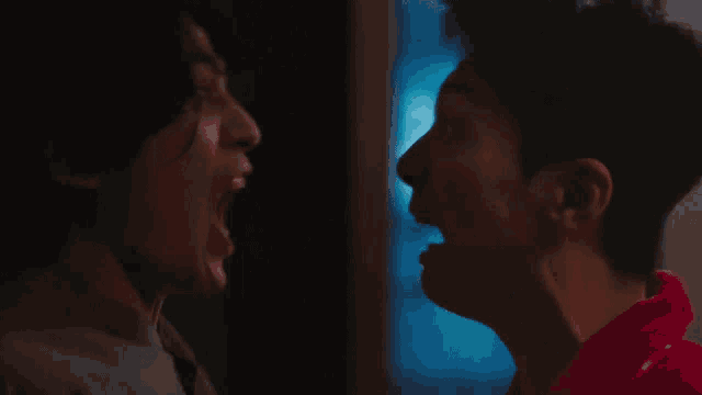 two men screaming at each other in a dark room