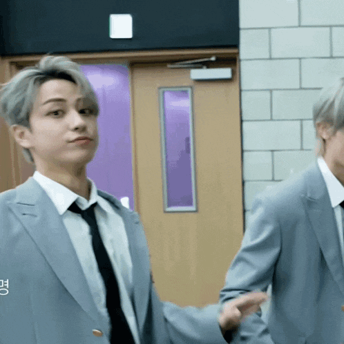 a man in a suit and tie stands next to another man in a suit