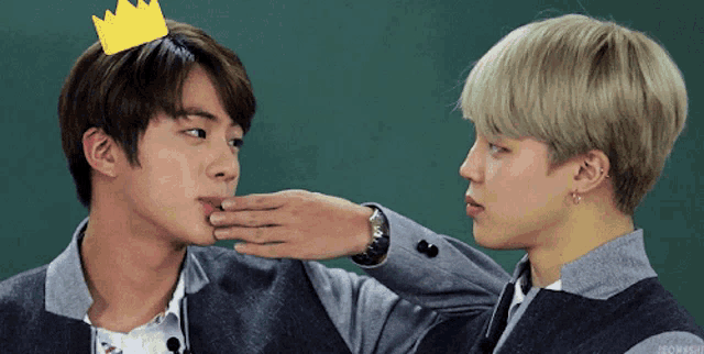 a boy with a crown on his head is being kissed by another boy