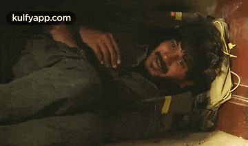 a man with a beard is laying on the floor with his hand on his head .