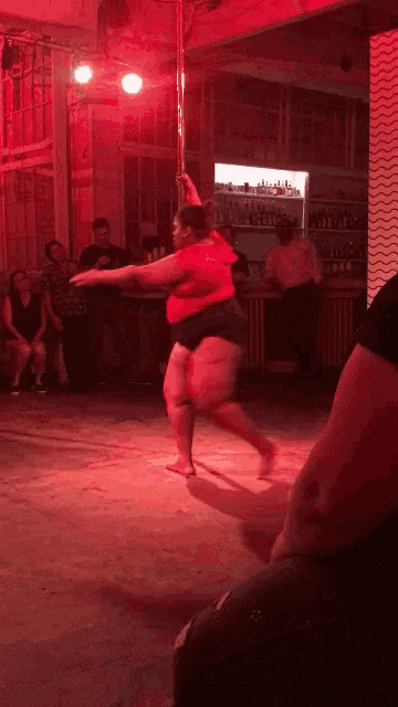a woman is dancing on a pole in front of a crowd