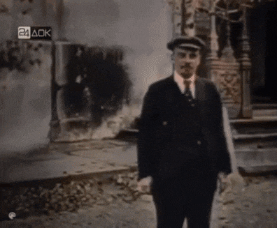 a man in a suit and hat is standing in front of a building with 24 ack written on the bottom right