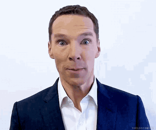 a man in a blue suit and white shirt is making a funny face .
