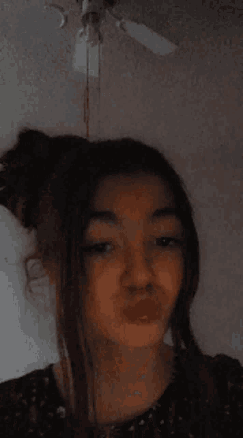 a girl is making a funny face with a ceiling fan behind her
