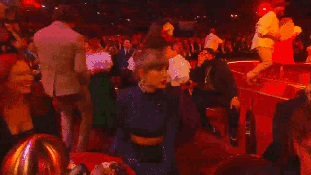 a crowd of people are dancing on a stage at a grammy awards show .