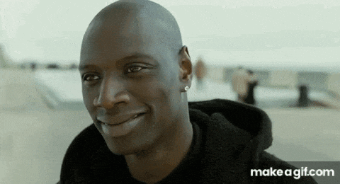 a bald man is smiling and wearing a black hoodie and earrings .
