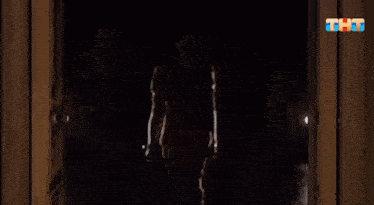 a man in a red suit is standing in a dark room .