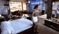 a woman in a maid apron is standing next to a bed in a bedroom