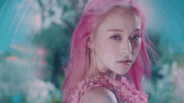 a woman with pink hair and blue eyes is wearing a pink dress