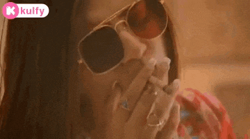 a woman wearing sunglasses is covering her mouth .