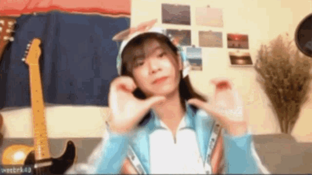 a girl wearing a hat is making a funny face in front of a guitar ..