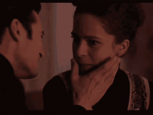 a man touching a woman 's face with his hand