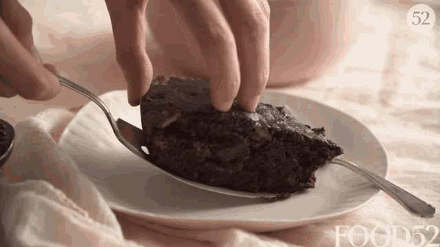 a person is taking a piece of chocolate cake with a fork from a plate that says food52