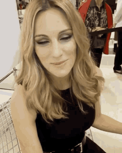 a woman in a black dress is sitting in a chair