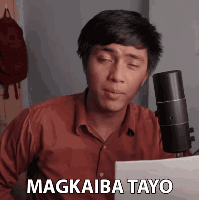 a man sitting in front of a microphone with the word magkaiba tayo written on the bottom