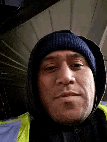 a man wearing a hooded jacket and a beanie is smiling