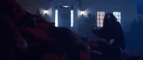 a group of people are standing in front of a house at night in a dark room .